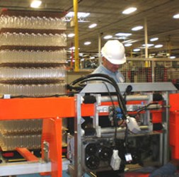 Machine operator is standing behind an orange machine.